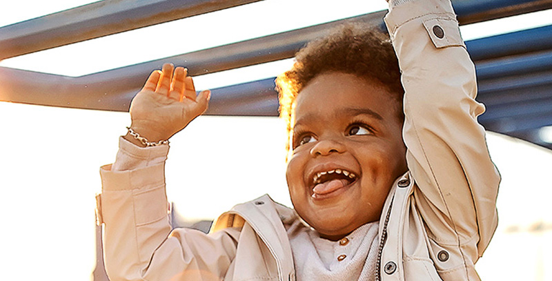 Closeup of a smiling child's face while he uses a climbing frame
