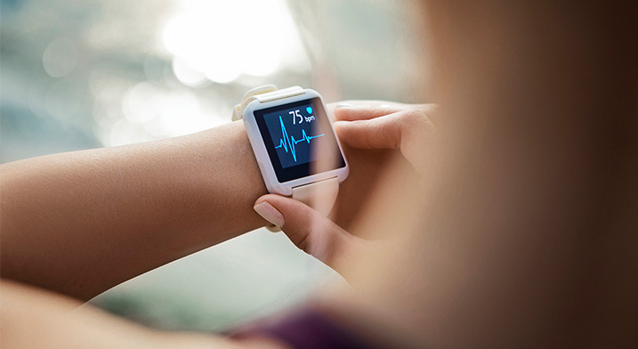 woman's hand operating a smartwatch displaying heart rate