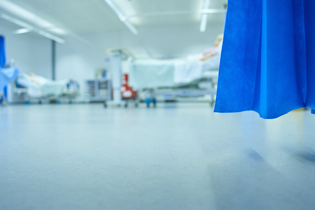 Out of focus hospital ward with cubicle curtain in foreground