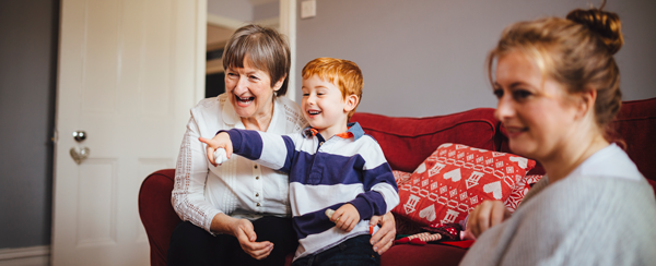 A family sat in a lounge or sitting room - young boy, woman and older female relative smiling