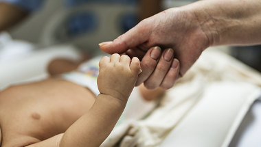 A mother and baby holding hands