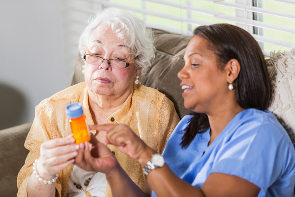 A medical professional showing a pill bottle to an older woman
