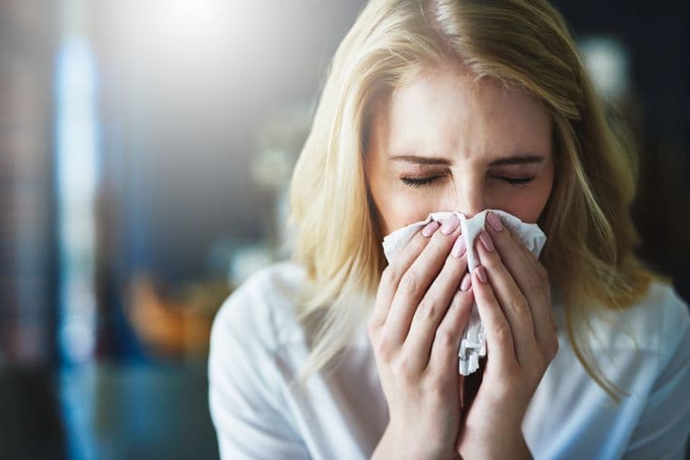 A woman with a dust allergy, sneezing into a handkerchief