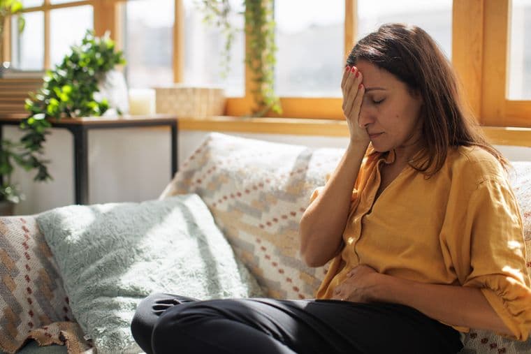 Woman, in physical discomfort, sat at home