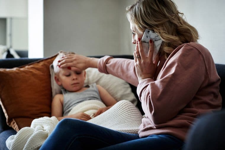 A child with pneumonia lays on the sofa next their carer