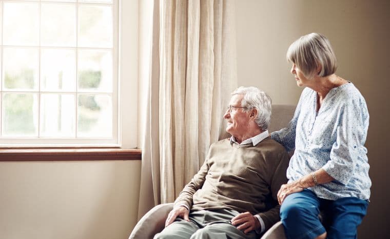 A senior couple sat looking out of a window thoughtfully