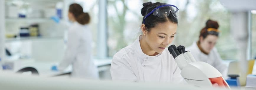 A woman looking into a microscope doing scientific research