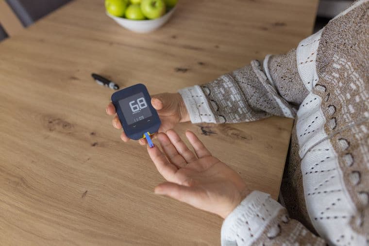 Woman checking blood sugar level at home