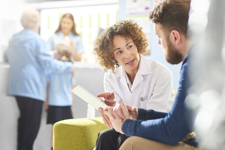 A clinician sitting in a chair chatting with a man