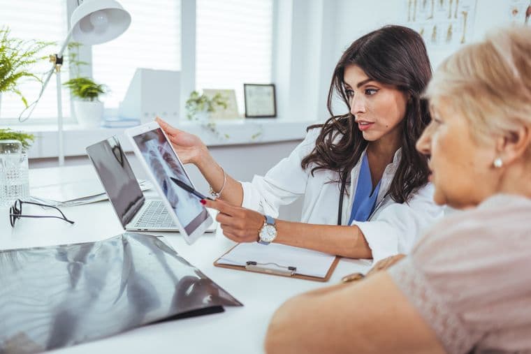 A clinician discusses an x-ray on a tablet with a patient