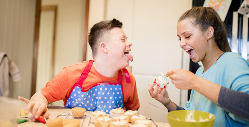 Female care worker baking with a boy who has Down's syndrome