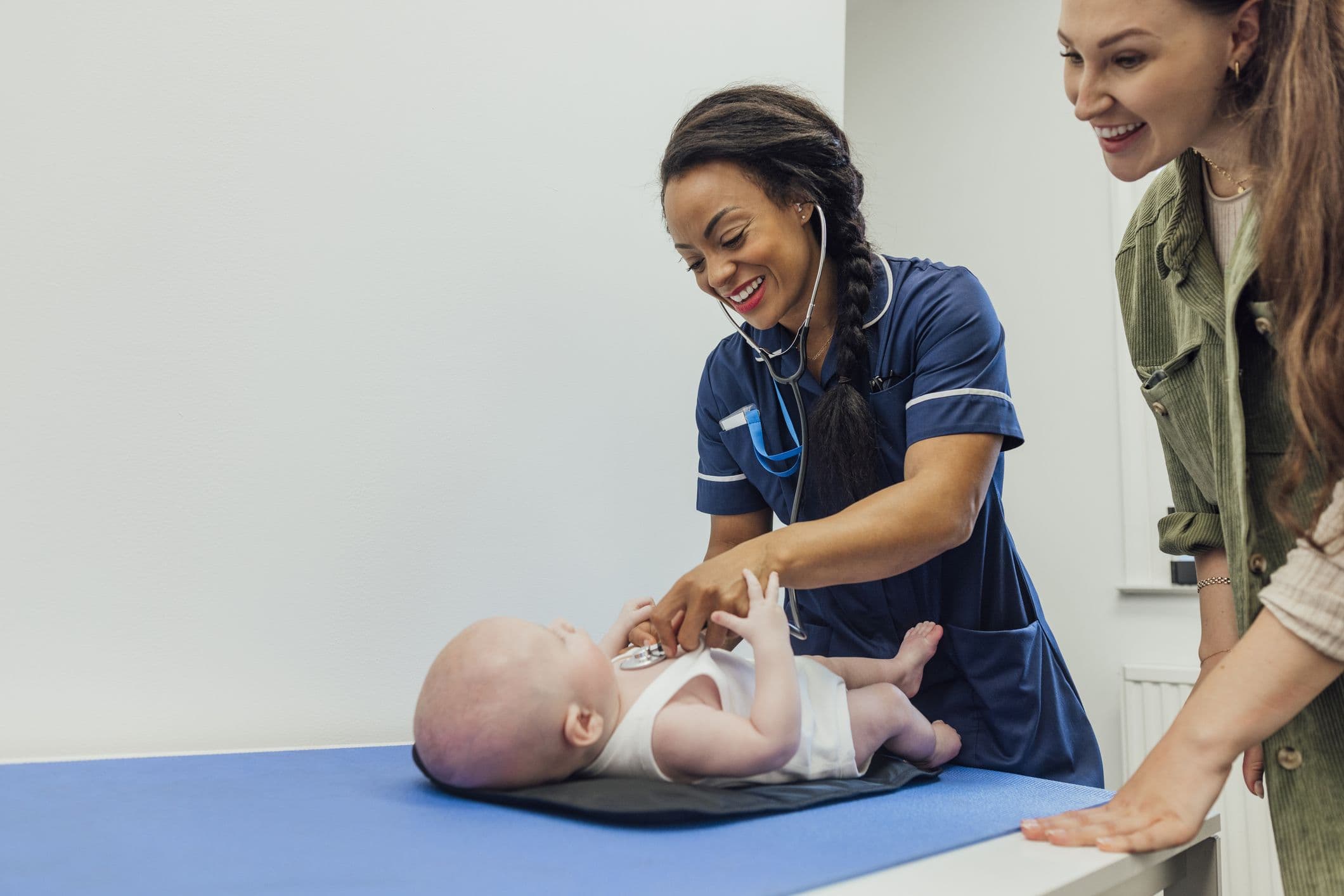 A woman with her baby attending a post natal care appointment with a nurse